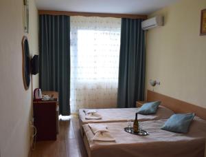 a bedroom with a bed with a table and a window at Ahilea Hotel - Free Pool Access in Balchik
