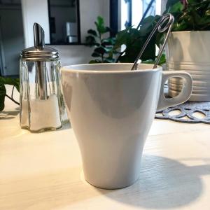 a white cup with a spoon in it on a table at Bed and Breakfast 33 in Ängelholm