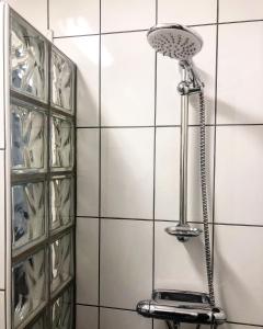 a shower in a bathroom with white tiles at Bed and Breakfast 33 in Ängelholm