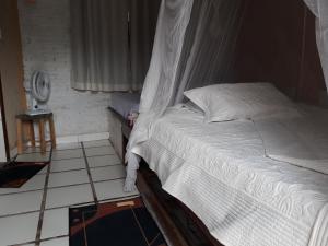 a bedroom with a white bed and a tiled floor at Ilha de Mato in Vale do Capao