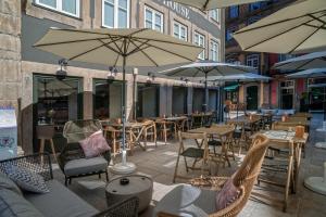 Porta Nova Collection House في براغا: فناء في الهواء الطلق مع طاولات وكراسي ومظلات