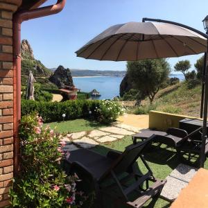 a patio with an umbrella and a table and chairs at L'Incanto Tanca Piras in Nebida