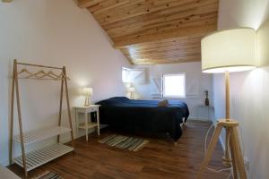 a bedroom with a blue bed and a wooden ceiling at Avó Rosa Guesthouse in São João da Ribeira