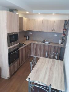 una cocina con armarios de madera y una mesa con sillas. en VIP Apartmány Žabník en Prievidza