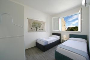ファヴィニャーナにあるCorte della Cavaのベッド2台と窓が備わる小さな客室です。