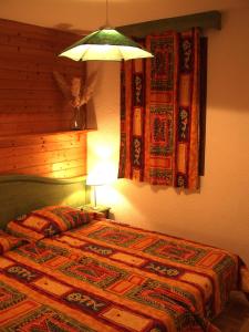 a bedroom with a bed with a lamp on it at CHALET LA LICORNE 1 - pied des pistes in Notre-Dame-de-Bellecombe