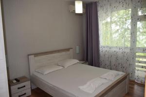 a bedroom with a white bed with a window at Ahilea Hotel - Free Pool Access in Balchik