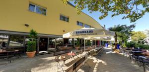 a cafe with benches and an umbrella in front of a building at Brau Art Hotel in Neckarsulm