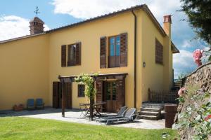 una casa amarilla con una mesa y sillas en el patio en Podere San Martino, en Montevettolini