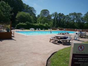 a swimming pool with picnic tables and a sign in front of it at Eryri Lodge in Caeathro