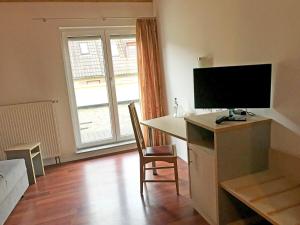 a living room with a tv and a desk with a computer at Brau Art Hotel in Neckarsulm