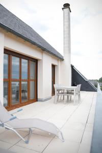 Cette maison blanche dispose d'une terrasse avec une table et des chaises. dans l'établissement Les Terrasses de Blois, à Blois