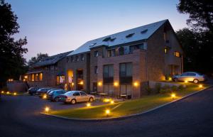 a large brick building with cars parked in a parking lot at Hotel - La Grande Cure in Marcourt