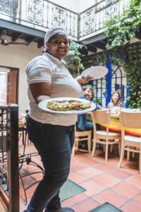a woman holding a plate with a pizza on it at La Rose B&B in Cape Town