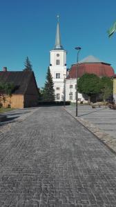 a cobblestone street in front of a white church at Old Town Family Apartment in Valga