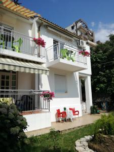 Casa blanca con sillas rojas y mesa en Guest House Vila Bak, en Budva