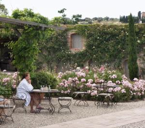 a woman sitting on a bench in front of a garden at Relais Sant'Elena in Bibbona