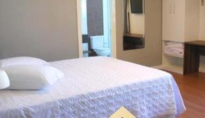 1 dormitorio con 1 cama blanca y suelo de madera en Hotel Jacuí, en Cachoeira do Sul