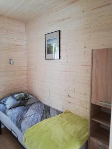 a small room with a bed in a wooden wall at Domek Pod Gruszą in Pierwoszyno