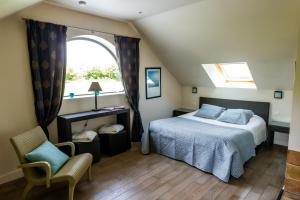 a bedroom with a bed and a window and a chair at La Ferme de l'Oudon & SPA in Berville