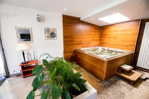 une baignoire jacuzzi dans une pièce ornée de plantes dans l'établissement La Ferme de l'Oudon & SPA, à Berville