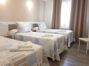 a room with three beds and a window at Pension Principado in Cangas de Onís