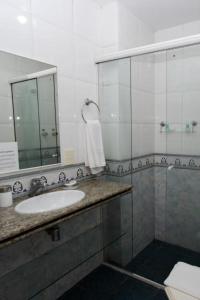 a bathroom with a sink and a shower with a mirror at Hotel Solar do Amanhecer in Niterói