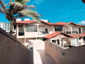 een gebouw met een palmboom ervoor bij Pousada Sol e Mar Ingleses in Florianópolis