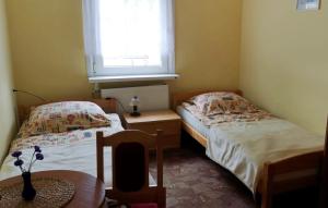 two beds in a small room with a window at Mały Biały Domek in Pobierowo