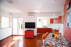 a kitchen with red cabinets and a table with a television at Apartments Dvori Novalja in Novalja