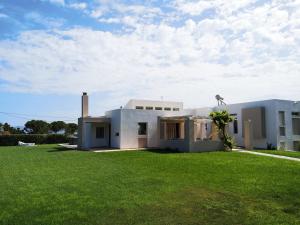 a white house with a green lawn in front of it at Villa Leonidas in Mastihari