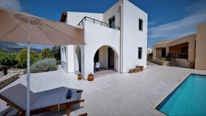 a white house with a swimming pool and an umbrella at Villa Anna in Asprouliánoi