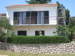 a man standing in the window of a white house at Apartment Stella in Malinska