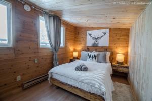 a bedroom with a bed with wooden walls and windows at Chalet Le Pti Loup - Les Chalets Spa Canada in La Malbaie