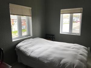 a bedroom with a white bed and two windows at Auberge Internationale Espace Globetrotter in Rimouski