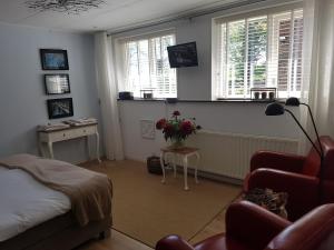 a bedroom with a bed and a table and windows at B&B de Panheide in Hooghalen