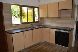 a kitchen with wooden cabinets and a black dishwasher at Serviced apartment (3 bedrooms) in Lusaka