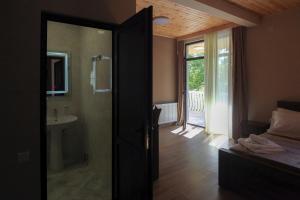 un bagno con porta aperta su una camera da letto con lavandino di Hotel Patriot a Mestia