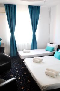 three beds in a room with blue curtains at Pension Iory`s in Techirghiol