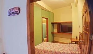 a small bedroom with a bed and a television at Posada Familiar El Dorado in Xilitla