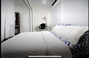 1 dormitorio con 1 cama blanca grande y escritorio en Luxury apartment with a/c next to chipichape mall, en Cali