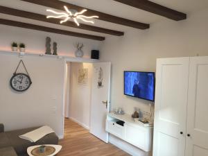 a living room with a couch and a tv on a wall at Haus Solymar App. Meerblick in Grömitz