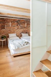 a bedroom with two beds against a brick wall at Apartamenty Monka in Toruń