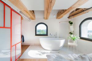 a bathroom with a white tub and two windows at Apartamenty Monka in Toruń