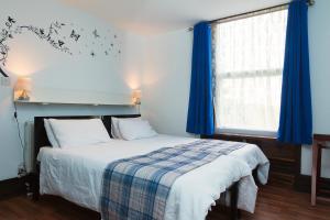 a bedroom with a bed and a window with blue curtains at Breeze Guest House in Bootle