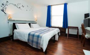 a bedroom with a bed and a window with blue curtains at Breeze Guest House in Bootle
