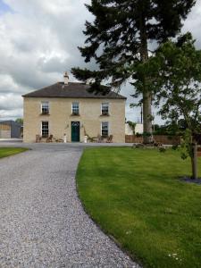 uma grande casa branca com uma árvore e uma entrada de cascalho em Abbeyview House em Abbeyshrule