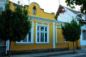 una casa amarilla con ventanas blancas en una calle en VINTAGE in Old Town, en Kecskemét