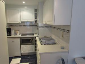 a small kitchen with white cabinets and a sink at Maurdy in Westende-Bad
