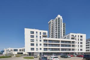 two tall white buildings with cars parked in a parking lot at Apartament Premium Aquatower Reda in Reda